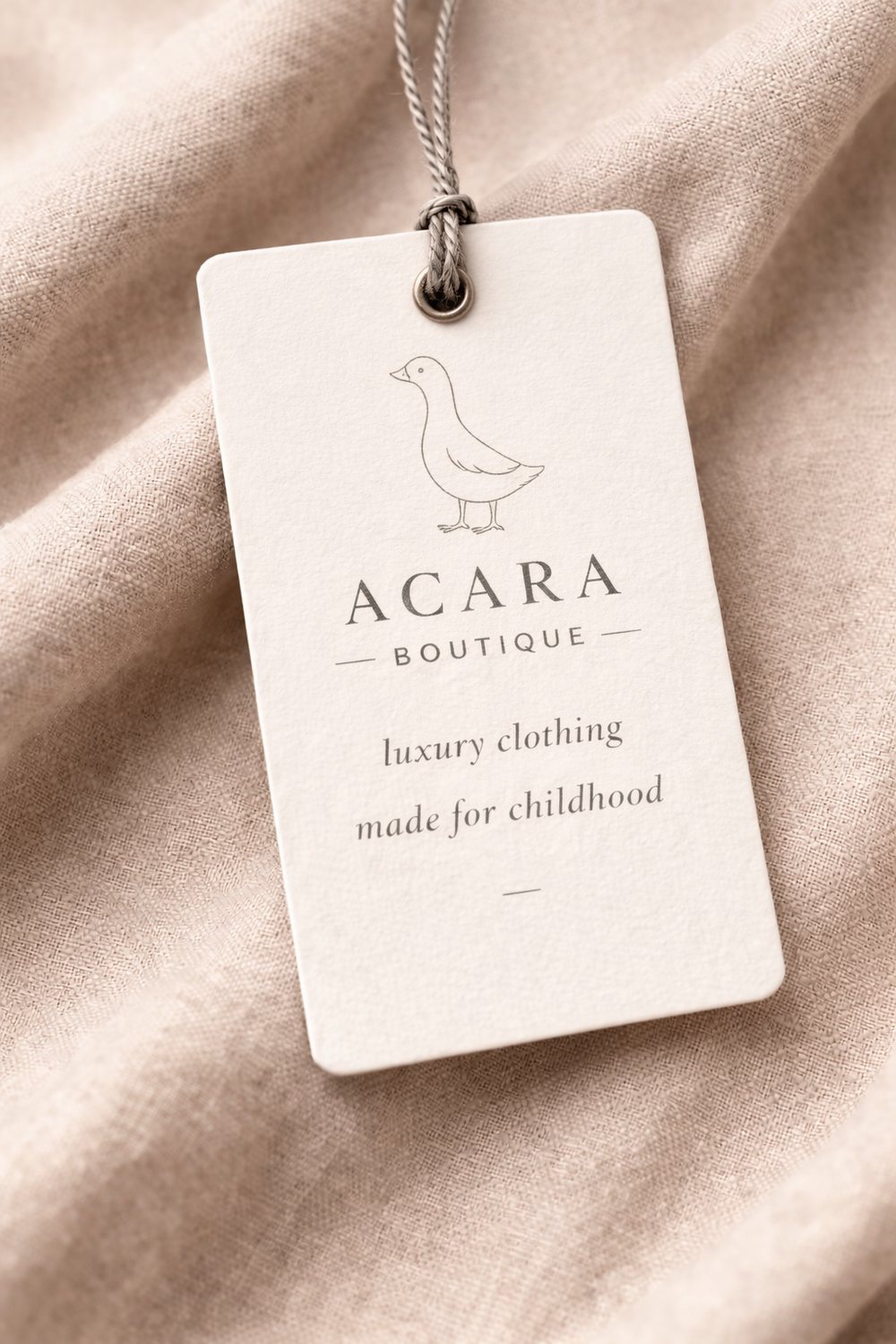 The Acara hang tag with its goose mark, resting on folded linen