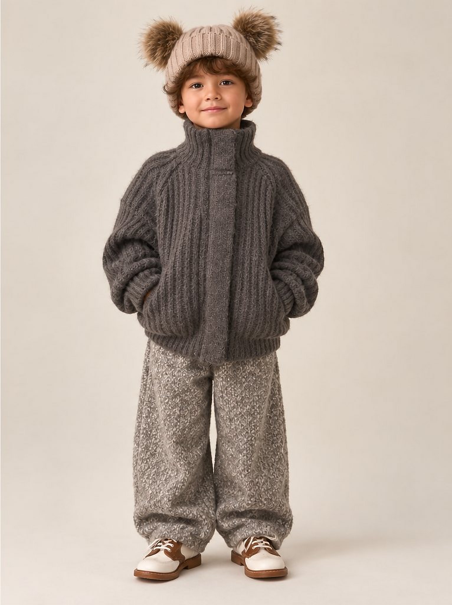 A boy in the charcoal ribbed zip cardigan and pom-pom beanie