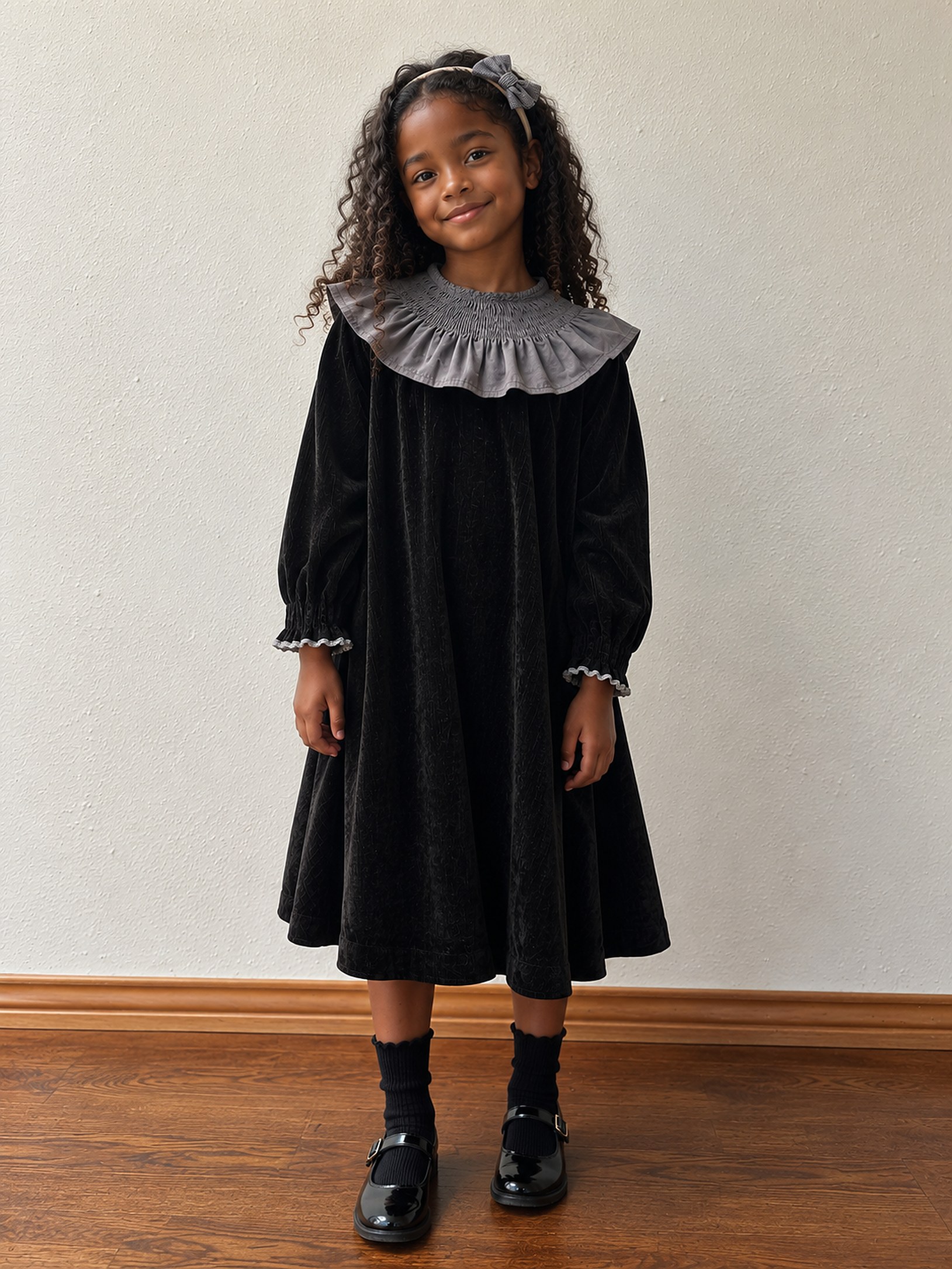 A girl in the black velvet smocked-collar dress with Mary Janes